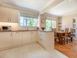 a kitchen with white cabinets and a table with chairs at Gorse Hill in Boldre