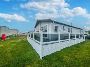 a white house with a porch on a lawn at Stunning 6 Berth Lodge With Partial Sea Views In Suffolk Ref 68007cr in Lowestoft