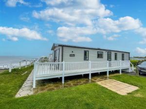 a mobile home with a white fence and the ocean at Beautiful Caravan With Stunning Sea Views At Haven Hopton Ref 80001h in Great Yarmouth