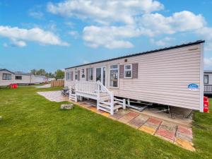 een grote metalen trailer met een veranda op een gazon bij By The Seaside Dog Friendly Caravan At Haven Hopton In Norfolk Ref 80015w in Great Yarmouth