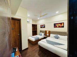 a hotel room with two beds and a desk at Hotel Akasa Inn in Mumbai
