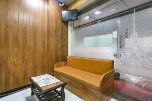 a room with a bench and a table and a tv at Hotel Akasa Inn in Mumbai