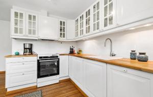 a white kitchen with wooden floors and white cabinets at 2 Bedroom Lovely Home In Ebeltoft in Ebeltoft