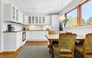 a kitchen with white cabinets and a wooden table and chairs at 2 Bedroom Lovely Home In Ebeltoft in Ebeltoft
