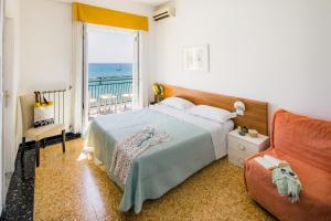 1 dormitorio con cama, ventana y sofá en Hotel Mayola, en San Bartolomeo al Mare