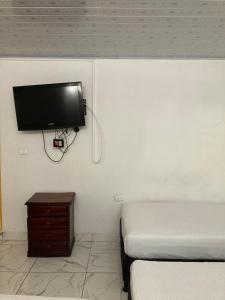 a room with two beds and a tv on the wall at Hotel Mallorca Estadio, Medellin in Medellín