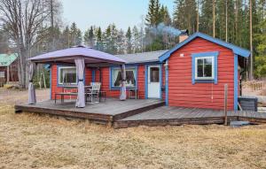 a red house with a deck with a table and an umbrella at Gorgeous Home In Orsa With Kitchen in Orsa