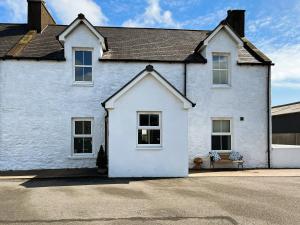 una casa blanca con un banco delante en The Old Cheese Loft, en Colfin