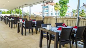 a row of tables and chairs with red napkins at Catty Cats Garden Hotel in Side