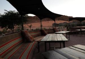 a picnic table and benches with tables and an umbrella at Desert stars in Wadi Rum