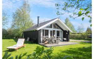 スラーエルセにあるAmazing Home In Slagelse With Wifiの黒いコテージ(テーブル、椅子付)