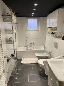 een badkamer met 2 wastafels, een bad en een toilet bij Flughafennahe 100 qm Oase mit eigenem Fitnessraum in Holzwickede
