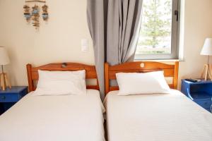 two twin beds in a room with a window at Nefeli Rooms in Agia Marina Nea Kydonias