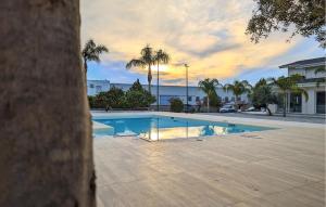 a swimming pool with palm trees and the ocean at Nice Home In Torranova With Kitchen in Torrenova