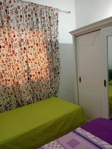 1 dormitorio con cama verde y cortina en Maison a louer à kelibia en Qulaybīyah