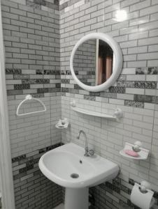 Baño blanco con lavabo y espejo en Maison a louer à kelibia en Qulaybīyah