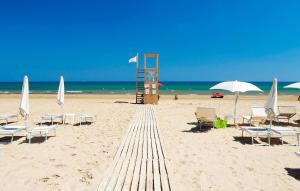 einen Sandstrand mit Liegestühlen und Sonnenschirmen und dem Meer in der Unterkunft Beach Front Home In Marina Di Modica in Marina di Modica