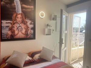 una camera da letto con un poster di una donna con ano di BEGOOD'IZ naturiste Studio indépendant au calme au coeur du village a Cap d'Agde