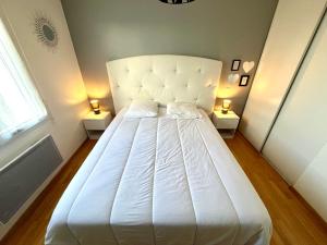 a large white bed in a room with two lamps at Maison familiale à Vairé in Vairé