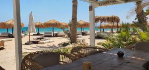 un tavolo sulla spiaggia con sedie e ombrelloni di Soma Bay Ambiance - Relaxed Apartment - Next to The Breakers a Hurghada