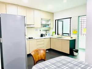 eine Küche mit weißen Schränken, einem Tisch und einem Stuhl in der Unterkunft Convenient Rare house in central city in Singapur