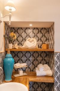 baño con estanterías con toallas y jarrón azul en Maison Fernanda, en SantʼAgata sui Due Golfi