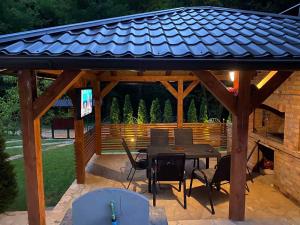 a wooden pavilion with a table and chairs and a television at Forest House between Sarajevo & Vlasic in Busovača