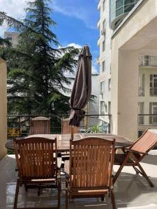 un patio con una mesa con sombrilla y sillas en Chavchavdze VAKE - 1BR Apartment, en Tiflis