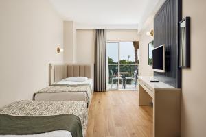 ein Hotelzimmer mit 2 Betten und einem Schreibtisch in der Unterkunft Seaden Sea World Resort & Spa All Inclusive in Kizilagac