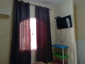 ventana con cortina roja y TV en Canto do Casarão, en Santos