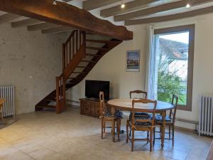 een eetkamer met een tafel en stoelen en een trap bij Maison dans belle longère - La Serrerie in Thenay