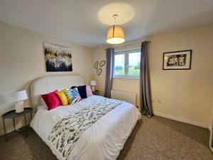 a bedroom with a large white bed with colorful pillows at Sensational Stay Apartments @ Torwood in Edinburgh