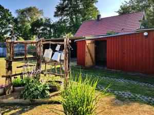 un granero rojo con una silla delante en An der Brake, Bungalow, en Prerow