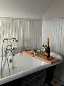 a bath tub with a bottle of wine and a glass at The Old Barn in Fivemiletown