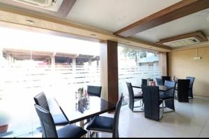 a dining room with tables and chairs and a large window at Ganpati Hotel in Bhopal