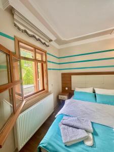 a bedroom with a bed with blue sheets and a window at Konak Grand Apart in Uzungol