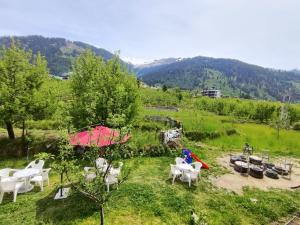 a group of chairs and tables in a field at Hotel Raj Palace Manali in Manāli