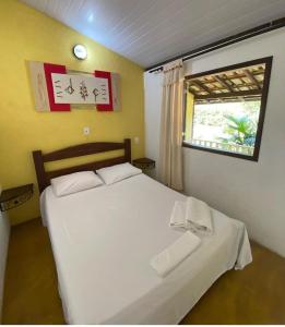 1 dormitorio con cama blanca y ventana en Pousada Embaubas, en Serra do Cipo