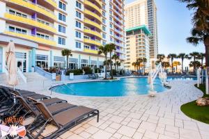 a swimming pool with lounge chairs and a building at 24th Floor 3 BR Resort Condo Direct Oceanfront Wyndham Ocean Walk Resort Daytona Beach 2425 in Daytona Beach