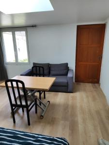 uma sala de estar com uma mesa e um sofá em studio independant avec jardin au calme em Neuilly-Plaisance