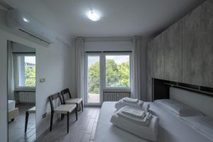 - une chambre avec un grand lit, des chaises et des fenêtres dans l'établissement Holiday Apartments Bellariva, à Riva del Garda