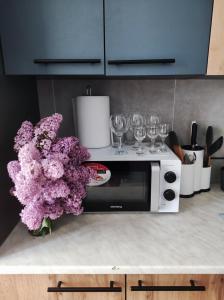 una cucina con forno a microonde e un bancone con fiori viola di Апартаменти в центрі Хмельницького (біля ТРЦ ЛибідьПлаза) a Chmel'nyc'kyj