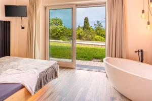 ein Bad mit einer Badewanne und einem großen Fenster in der Unterkunft Villa Lakeview Heaven in Lonato
