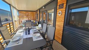 uma sala de jantar com mesas e cadeiras numa varanda em CHARTA mobile home Bimbo em Pirovac