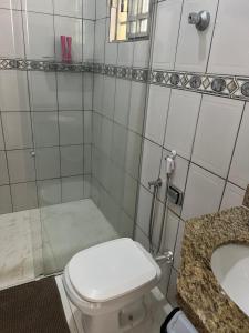 Baño blanco con aseo y lavamanos en Casa 400m do shopping, en Governador Valadares