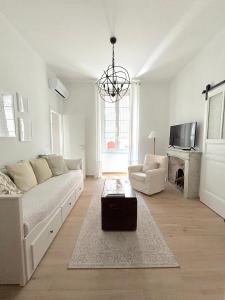 a white living room with a couch and a tv at Casa verde in Ventimiglia