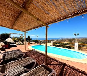 basen z krzesłami i dachem ze słomy w obiekcie Casa Nuestro Sueño, fantastic sea views w mieście Torrox
