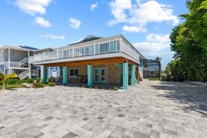 a house with a balcony on top of a driveway at Seaside oasis studio with heated pool in Fort Myers Beach