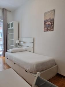 a white bedroom with a bed and a chair at Apt by Trieste University in Trieste