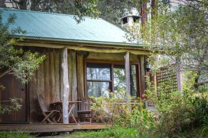 a cabin in the woods with a table and a chair at Ghost Hill Road Retreat in Bilpin